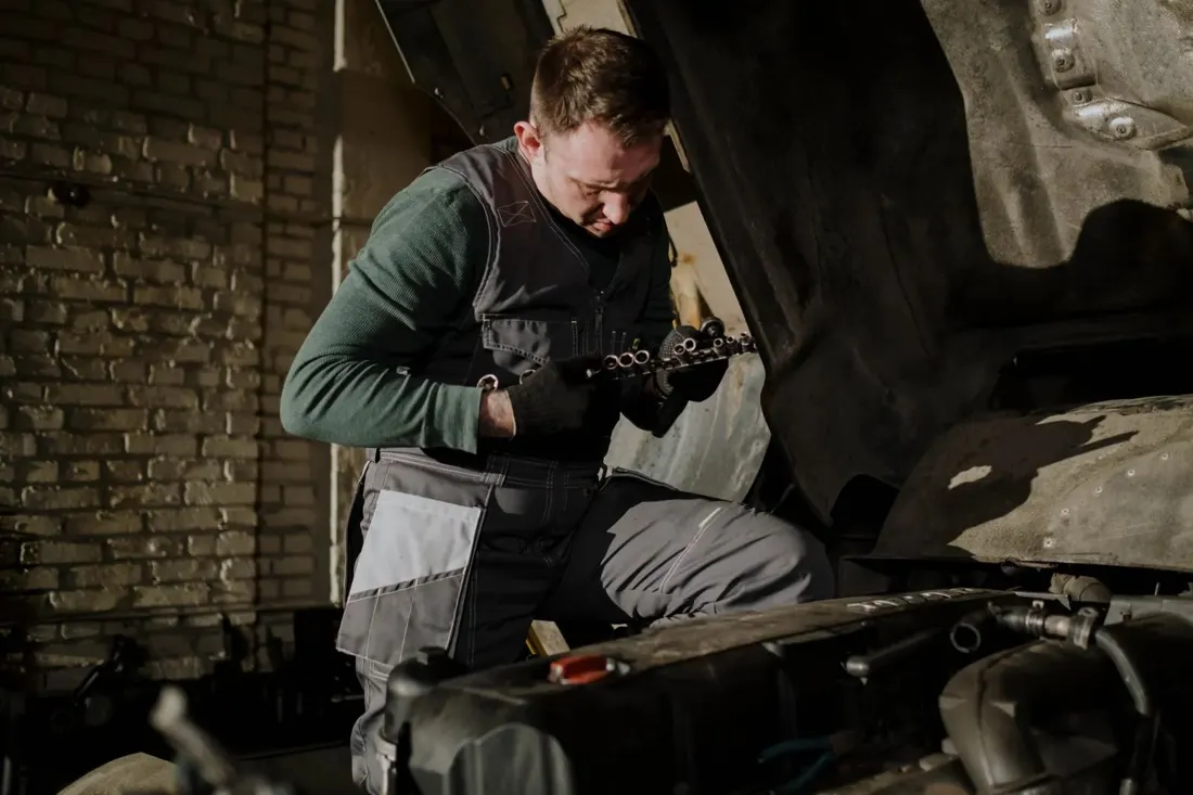 Mechanic holding a part beside an open engine