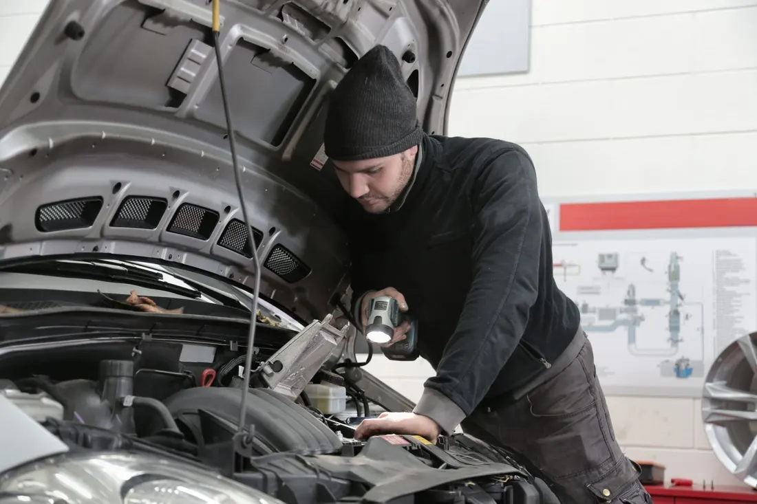 Mechanic working in an engine bay under a work light